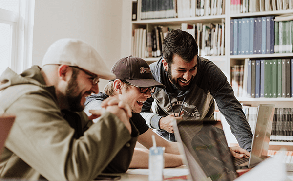 Men laughing around laptops