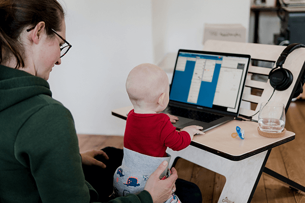 A woman with a baby working at a laptop