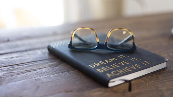 Dream it. Believe it. Achieve it. Book and sunglasses.